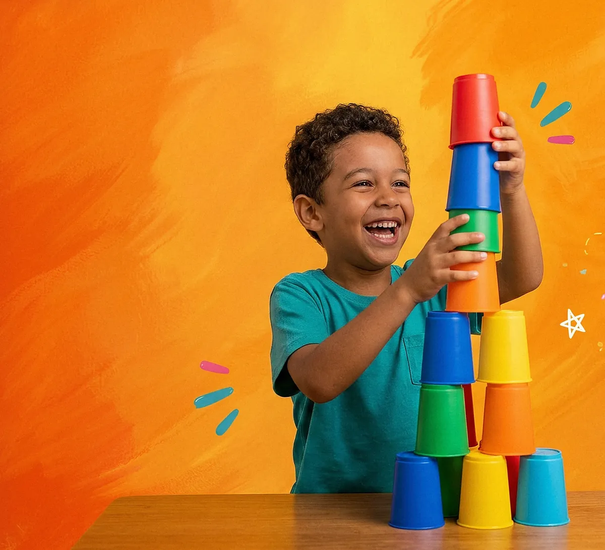 Menino rindo enquanto empilha uma torre de copos coloridos